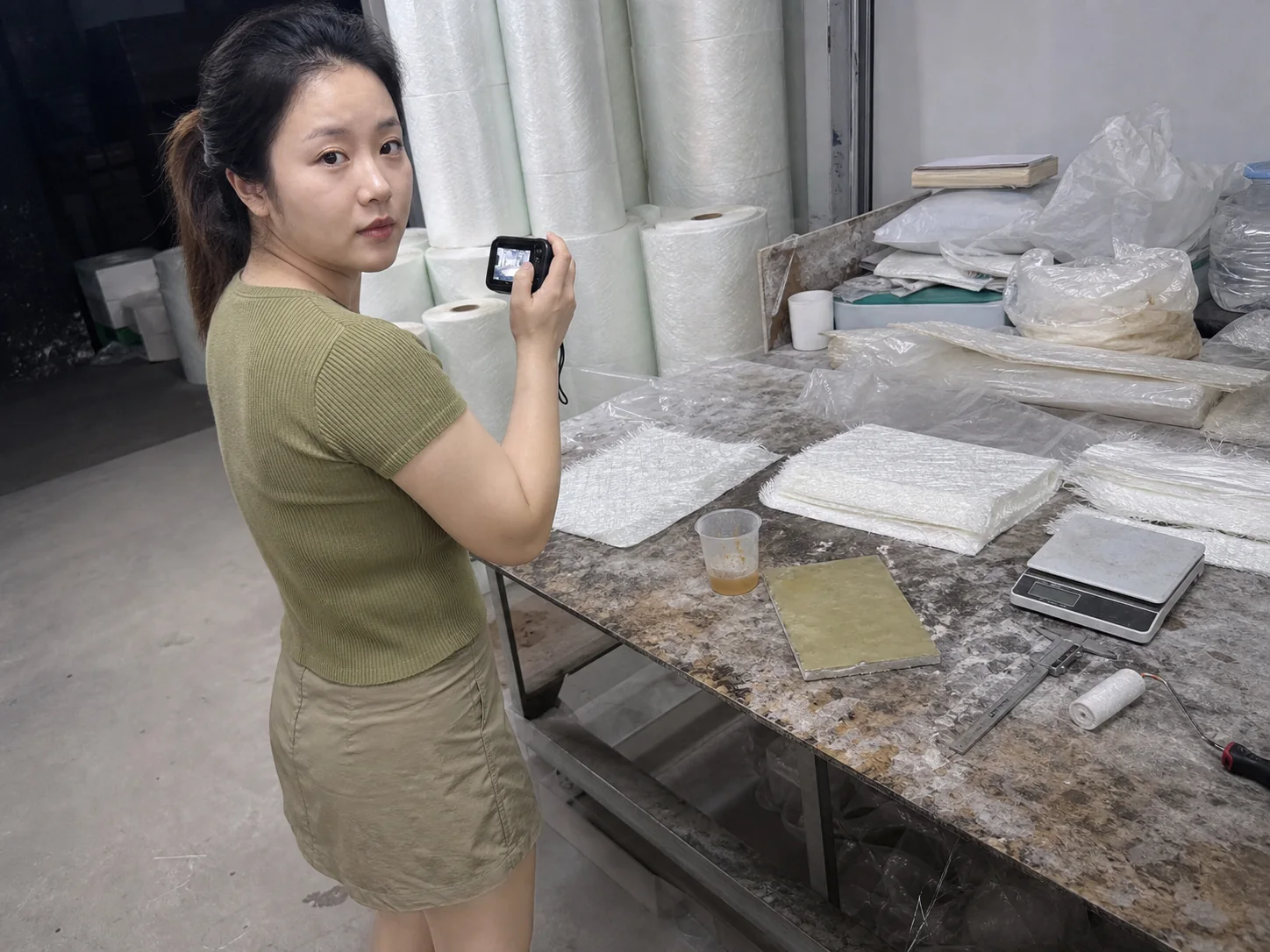 女性自媒体拍摄人员在复合材料试样台用相机记录玻纤毡、树脂和层压样板