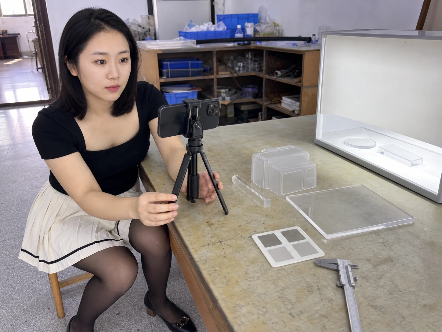 女性自媒体拍摄人员在透明材料样品室用手机记录PMMA样件和表面效果